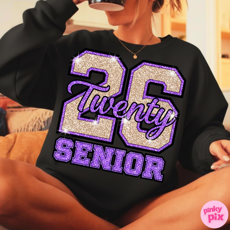 May include: Black sweatshirt with a glittery design featuring the number "26", the word "Twenty" in script, and the word "SENIOR" in purple block letters. The design has a purple and gold color scheme.