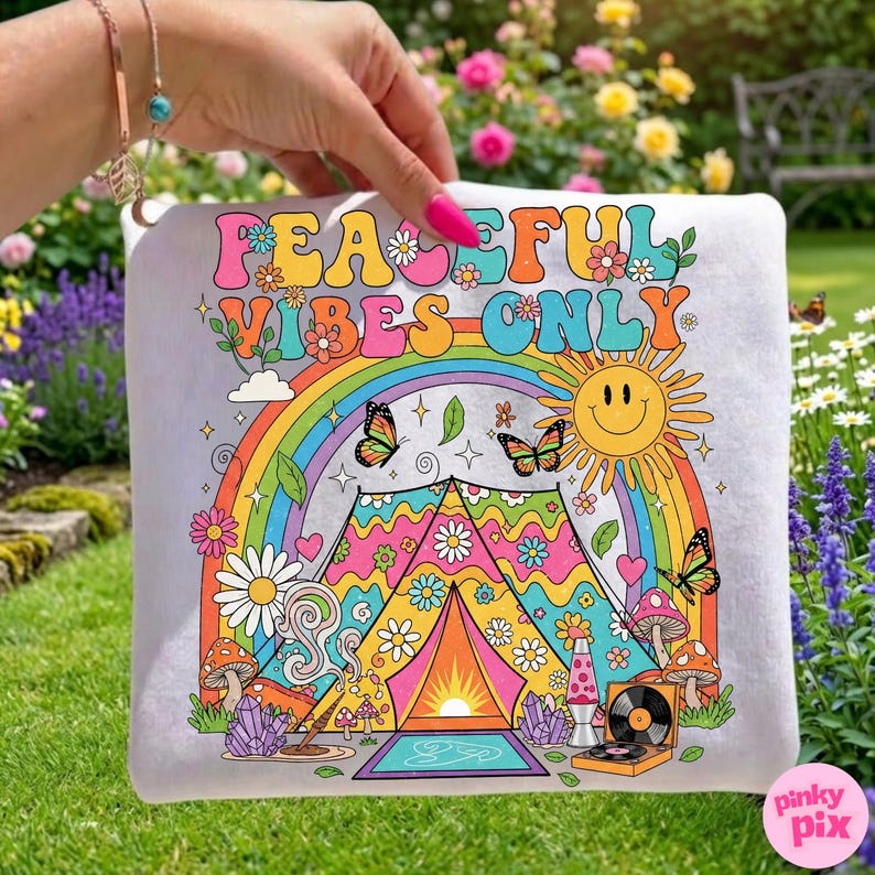 May include: A white pillow with a colorful graphic design featuring a rainbow, butterflies, a smiling sun, and the text "PEACEFUL VIBES ONLY." The design includes a tent, flowers, and a record player, evoking a retro, hippie aesthetic.