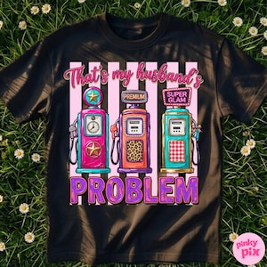 May include: Black t-shirt with a graphic of three vintage gas pumps in pink, orange, and teal, with the text "That's my husband's PROBLEM" in pink and purple. The pumps have star and leopard print details.