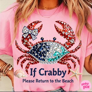 May include: Pink t-shirt featuring a bedazzled crab design with red, white, blue, and turquoise accents. The crab has a bow and the text "If Crabby, Please Return to the Beach". A seashell and starfish are also visible.