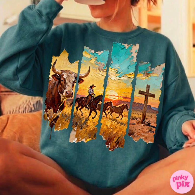 May include: Teal-colored sweatshirt featuring a Western-themed graphic. The design includes a bull, a cowboy on horseback, and a cross against a sunset backdrop. The artwork has a textured, painted appearance.