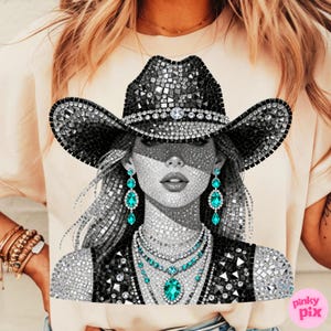 May include: A graphic tee featuring a mosaic-style portrait of a woman wearing a bedazzled cowboy hat, earrings, and necklace. The design is primarily black, white, and silver, with turquoise accents. The shirt is a light peach color.