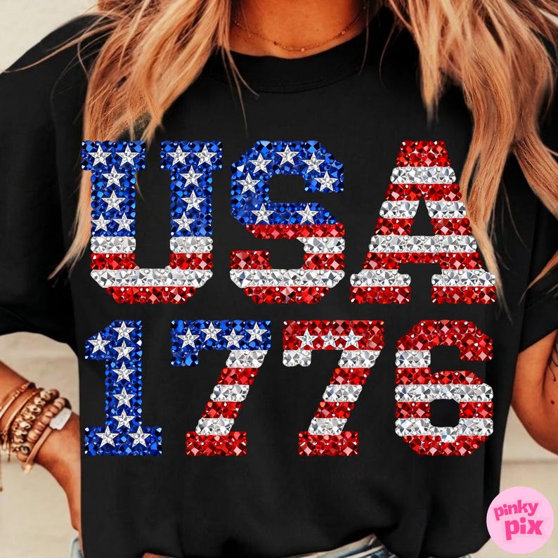 K&ouml;nnte beinhalten: Schwarzes T-Shirt mit dem Text "USA 1776". Die Buchstaben und Zahlen sind mit rot, wei&szlig; und blau glitzernden Sternen und Streifen verziert, die die amerikanische Flagge darstellen.