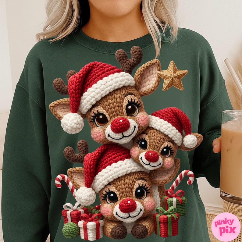 May include: A dark green sweatshirt featuring a festive design of three reindeer wearing Santa hats. The reindeer have red noses and are surrounded by gifts and candy canes. A gold star is also present in the design.