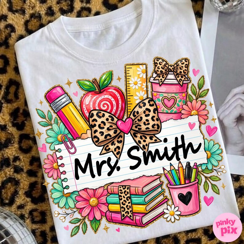 May include: White t-shirt featuring a colorful graphic design for a teacher. The design includes a pencil, apple, ruler, coffee cup, books, and the text "Mrs. Smith". The design incorporates floral elements and a leopard print bow.