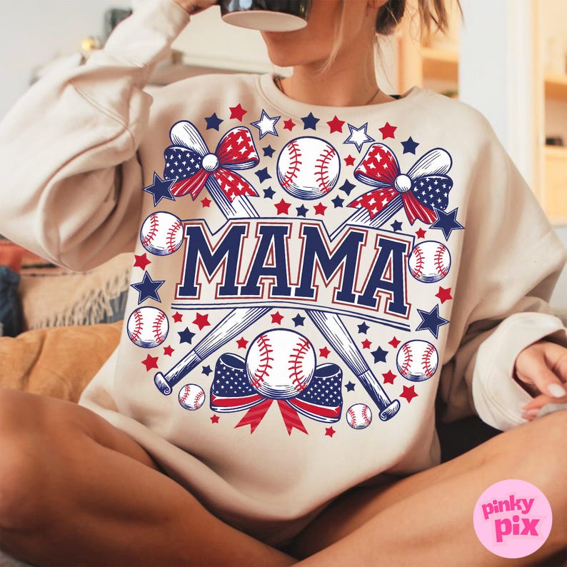 May include: A beige sweatshirt with a baseball-themed design. The design features two crossed baseball bats, baseballs, stars, and a red, white, and blue bow. The word "MAMA" is written in large, bold letters.