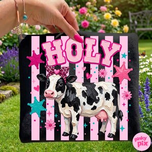 May include: Black square pillow with a cow illustration. The cow is black and white with a pink bow and udder. The pillow has pink and black stripes with the word "HOLY" in pink letters. Pink stars and flowers decorate the pillow.