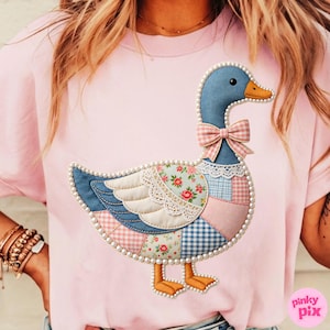 K&ouml;nnte beinhalten: Rosa T-Shirt mit einem G&auml;nsemotiv im Patchwork-Stil. Die Gans hat einen blauen Kopf, einen orangefarbenen Schnabel und eine rosa Schleife. Der K&ouml;rper besteht aus verschiedenen gemusterten Stoffen, darunter Blumen und Vichy, und ist mit Perlen umrandet.