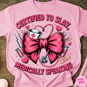 May include: Pink t-shirt with the text "CERTIFIED TO SLAY, MEDICALLY SPEAKING" in a stylized font. The graphic features a large pink bow, a nurse's hat, a stethoscope, syringes, and hearts.