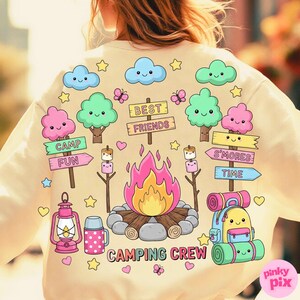 May include: Cream-colored sweatshirt with a colorful camping-themed graphic. The design includes cartoon trees, clouds, a campfire, marshmallows, and the words "CAMPING CREW", "CAMP FUN", "S'MORES TIME", and "BEST FRIENDS".