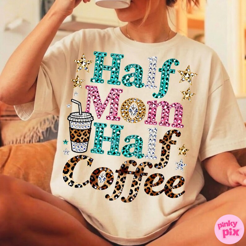 Może przedstawiać: Kremowa koszulka z napisem "Half Mom Half Coffee" w kolorze turkusowym, r&oacute;żowym i w panterkę. Projekt zawiera grafikę filiżanki kawy i akcenty gwiazd. Koszulka jest w stylu casual i wygodnym.