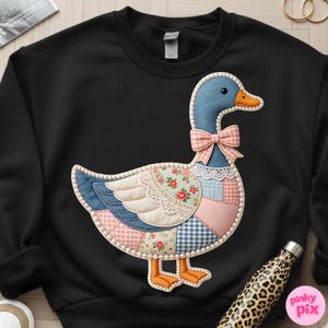 K&ouml;nnte beinhalten: Schwarzes Sweatshirt mit einem skurrilen G&auml;nsemotiv. Die Gans ist mit einem Patchwork aus floralen, Vichy- und Jeansstoffen verziert, akzentuiert mit einer rosa Schleife und Perlenbesatz. Die Gans hat einen blauen Kopf und einen orangefarbenen Schnabel und F&uuml;&szlig;e.