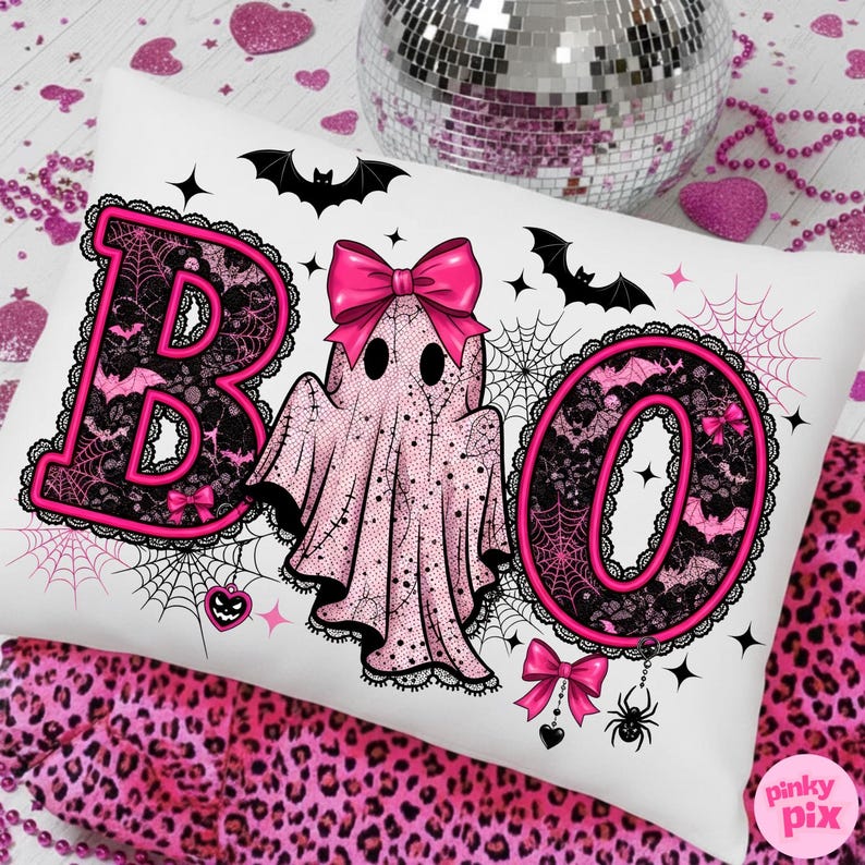 Puede incluir: Coj&iacute;n rectangular blanco con tem&aacute;tica de Halloween. La palabra "BOO" est&aacute; escrita con letras de encaje rosa y negro. Un fantasma rosa con un lazo est&aacute; en el centro. Murci&eacute;lagos, telara&ntilde;as y lazos decoran el coj&iacute;n. Una bola de discoteca y tela con estampado de leopardo rosa est&aacute;n en el fondo.