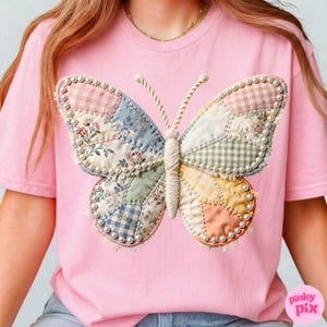 May include: A light pink t-shirt featuring a large, central butterfly graphic. The butterfly is composed of various patchwork fabric segments in floral, gingham, and solid patterns, outlined with small white beads and a central corded body.