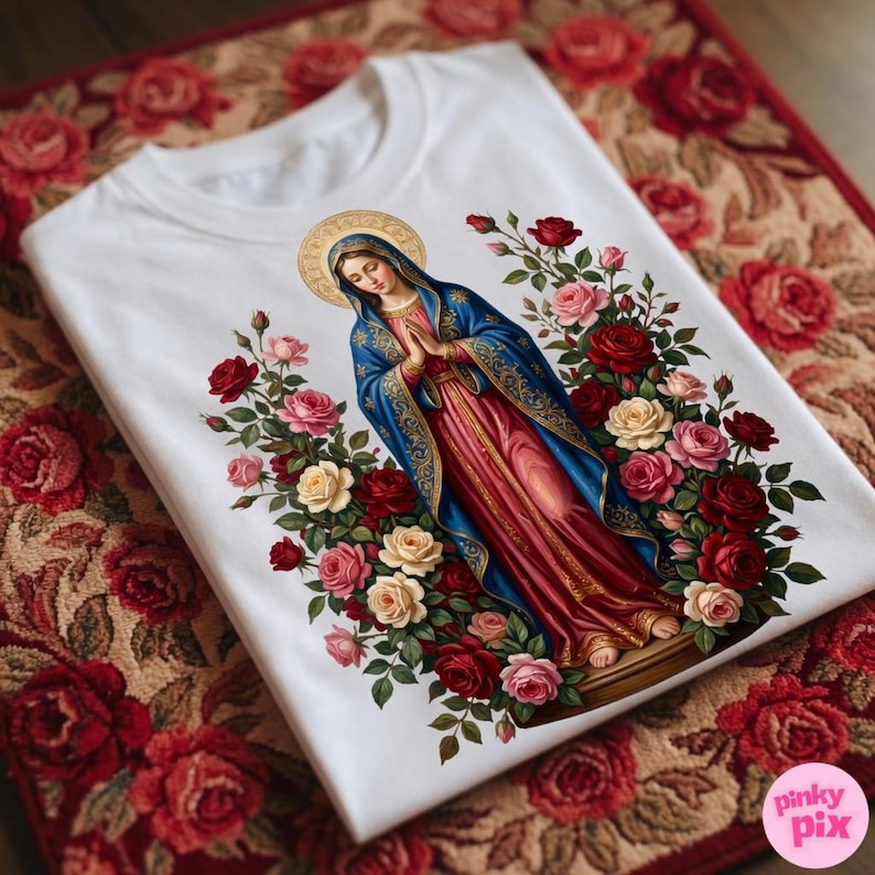 May include: White t-shirt featuring a religious illustration of a woman in a blue and red robe, surrounded by roses in various colors. The design includes a gold halo and is set against a floral background.