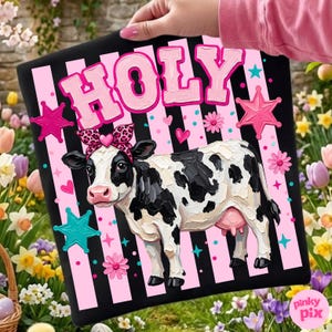 May include: A black and pink striped sign with the word "HOLY" in pink letters. The sign features a black and white cow wearing a leopard print bow. Pink stars, hearts, and flowers decorate the sign.