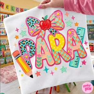 May include: White fabric with the word "PARA" in colorful, textured letters. A large bow with an apple, pencil, and ruler are also featured. The design includes stars and floral accents, perfect for a teacher or classroom.
