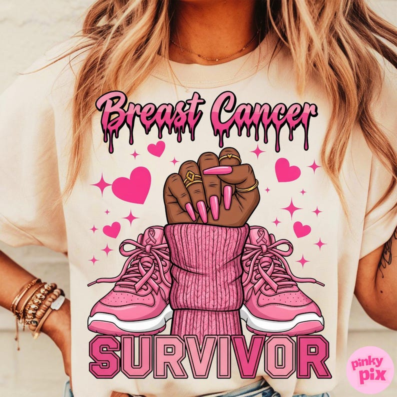 May include: Cream-colored t-shirt with a pink graphic design. The design includes the words "Breast Cancer Survivor" in pink, a raised fist, pink hearts, and pink sneakers.