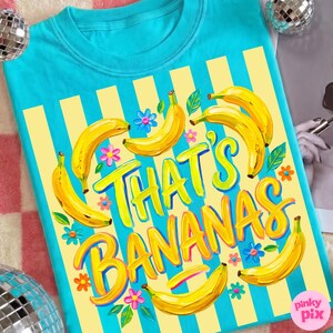 Pu&ograve; includere: Una maglietta turchese con un design a righe gialle e blu. La maglietta presenta la frase "THAT'S BANANAS" in giallo, circondata da illustrazioni di banane gialle, foglie verdi e fiori colorati. Un design divertente e giocoso.
