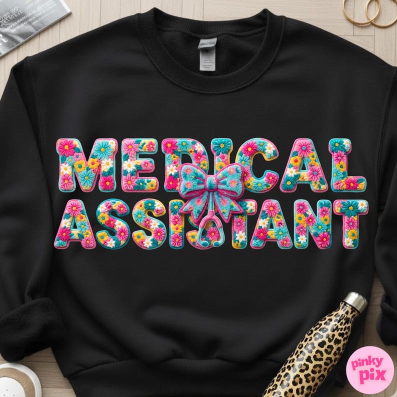 May include: Black sweatshirt with the words "MEDICAL ASSISTANT" in large, colorful, floral letters. A blue bow and stethoscope graphic are centered between the words. The sweatshirt is a crew neck style.