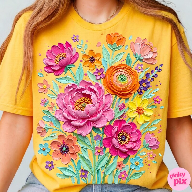 May include: Yellow t-shirt featuring a vibrant floral design. The graphic includes large pink peonies, orange ranunculus, and various other colorful flowers with green leaves. The design has a textured, painted appearance.