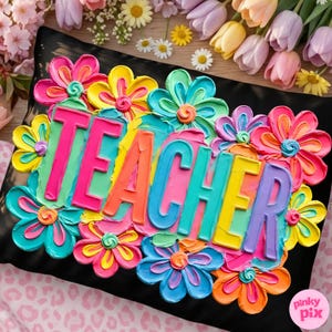 May include: Black pillow with the word "TEACHER" in colorful, raised letters, surrounded by vibrant, textured flowers in shades of pink, yellow, blue, and orange. The pillow is a decorative item.