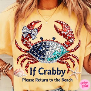May include: Yellow t-shirt with a crab graphic made of red, white, blue, and clear crystals. The crab has a bow on one claw. Text on the shirt reads "If Crabby, Please Return to the Beach."