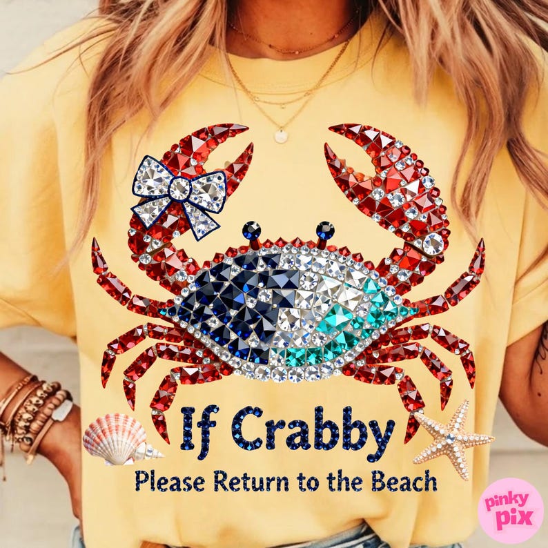 May include: Yellow t-shirt with a crab graphic made of red, white, blue, and clear crystals. The crab has a bow on one claw. Text on the shirt reads "If Crabby, Please Return to the Beach."