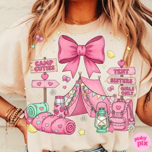 May include: A light beige t-shirt with a pink camping scene. The design includes a large bow, tent, and the words "Camp Cuties", "Tent Sisters", and "Girls Only". Butterflies, hearts, and a backpack are also featured.