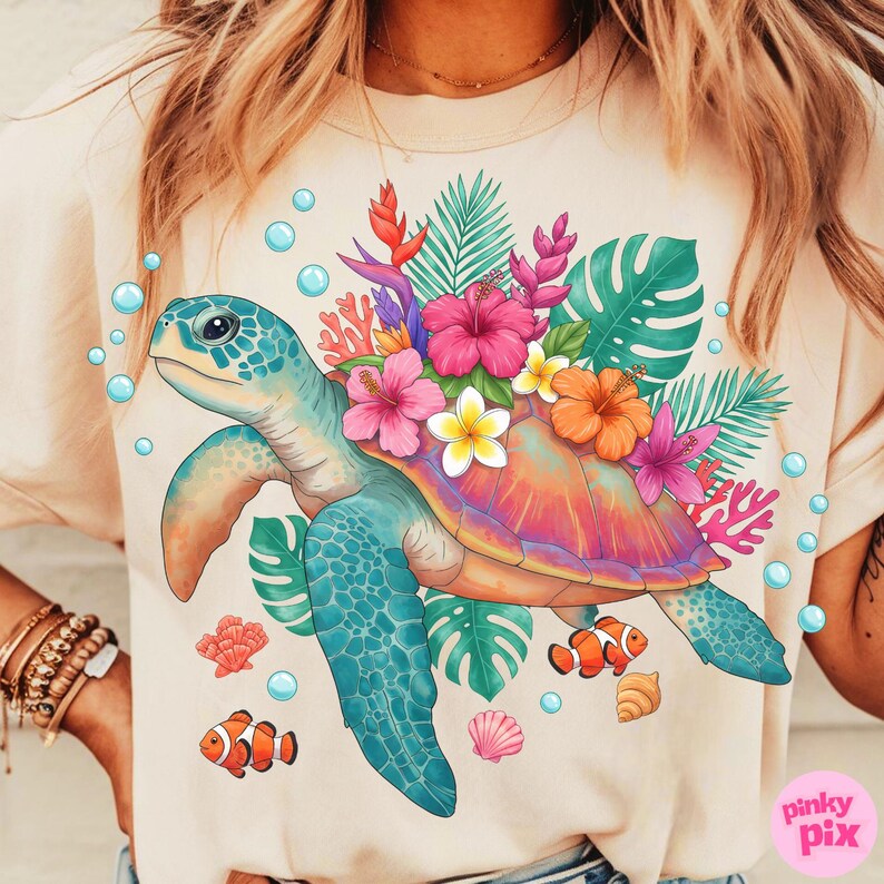 May include: A light beige t-shirt featuring a colorful sea turtle design. The turtle has a blue head and flippers, a multi-colored shell, and is surrounded by tropical flowers, coral, and fish. Bubbles and seashells complete the design.