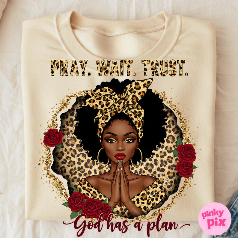 May include: A beige sweatshirt with a black and gold leopard print design. The design features a woman with a leopard print headband, praying with her hands clasped together. The text "Pray. Wait. Trust. God has a plan." is printed on the sweatshirt.