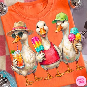 May include: Orange t-shirt featuring three cartoon ducks enjoying summer treats. One duck wears sunglasses and a straw hat, holding a drink. Another has a popsicle, and the third holds an ice cream cone. The shirt has the Pinky Pix logo.