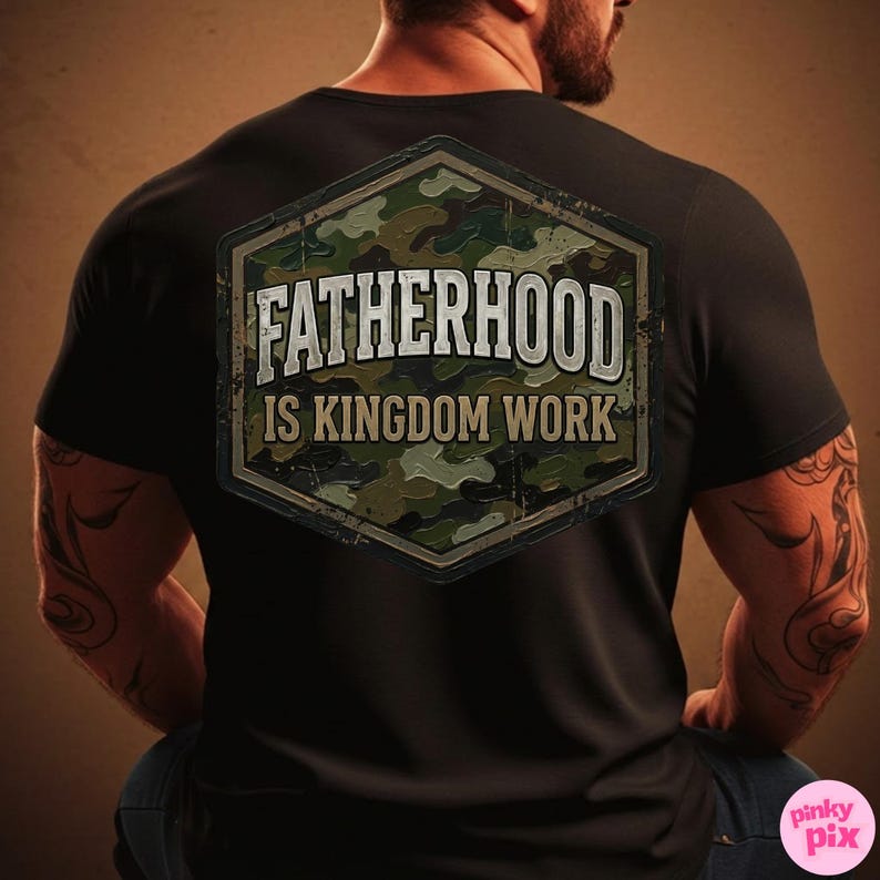 Pode incluir: Camiseta preta com um design de camuflagem e o texto "FATHERHOOD IS KINGDOM WORK" em branco. O design tem a forma de um hex&aacute;gono. A camiseta est&aacute; em uma pessoa.