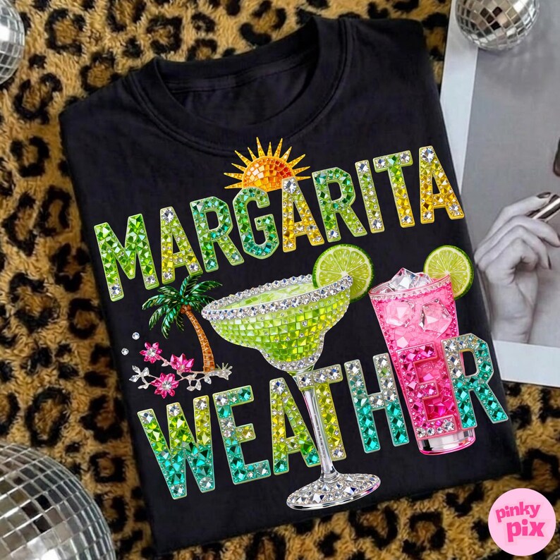 Peut inclure: T-shirt noir avec l'inscription "MARGARITA WEATHER" en lettres orn&eacute;es de bijoux. Le motif comprend un verre &agrave; margarita, un cocktail rose, un soleil, un palmier et des tranches de citron vert. Le t-shirt a un col rond.