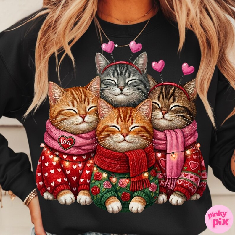 May include: Black sweatshirt featuring a graphic of four smiling cats. The cats wear sweaters, scarves, and heart-shaped headbands. The sweaters are red and green with heart and rose patterns. One scarf says "LOVE".