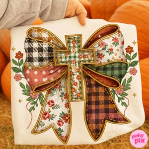 May include: A cream-colored decorative pillow featuring a large bow design with a cross in the center. The bow incorporates various patterns, including gingham, polka dots, and floral prints in shades of red, green, and brown. The cross is adorned with floral patterns.
