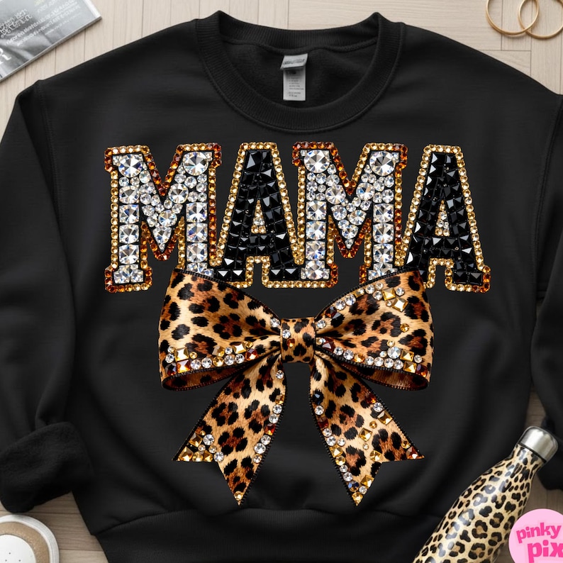 May include: Black sweatshirt with the word "MAMA" in jeweled letters and a leopard print bow. The word "MAMA" is outlined in gold and filled with clear and black rhinestones. The bow is also embellished with rhinestones.