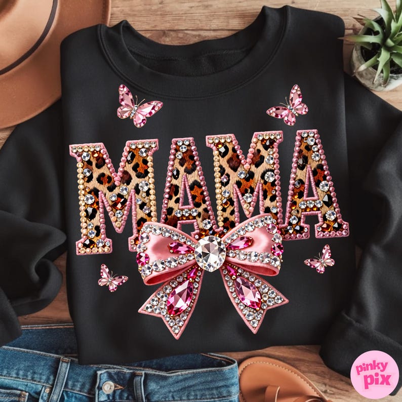 May include: Black sweatshirt with the word "MAMA" in leopard print, embellished with rhinestones. A pink bow with rhinestones and pink butterflies are also featured on the sweatshirt.