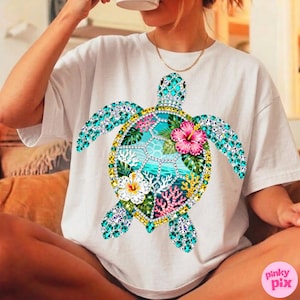 May include: White t-shirt featuring a colorful, bejeweled sea turtle design. The turtle's shell is adorned with turquoise, pink, and yellow gemstones, and the design includes tropical flowers and coral. The shirt is a casual, everyday wear item.