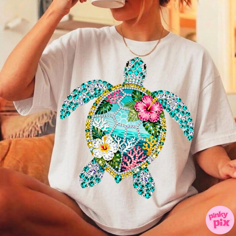 May include: White t-shirt featuring a colorful, bejeweled sea turtle design. The turtle's shell is adorned with turquoise, pink, and yellow gemstones, and the design includes tropical flowers and coral. The shirt is a casual, everyday wear item.