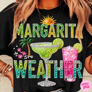 Peut inclure: T-shirt noir avec l'inscription scintillante et color&eacute;e "MARGARITA WEATHER". Le motif comprend un verre &agrave; margarita, une boisson rose, un soleil, un palmier et des tranches de citron vert.