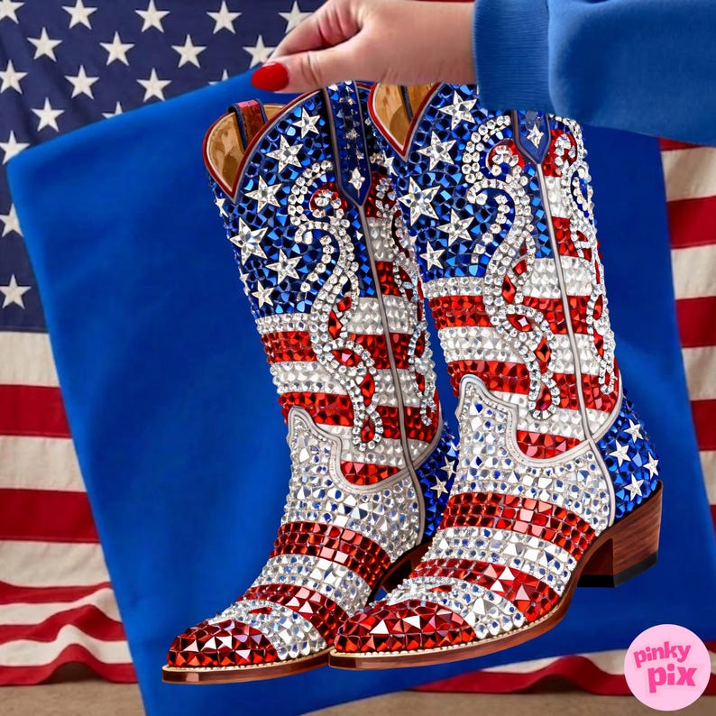 May include: A pair of cowboy boots with a patriotic design. The boots feature red, white, and blue rhinestones arranged in the pattern of the American flag. The boots have a brown heel and are held against a blue background.