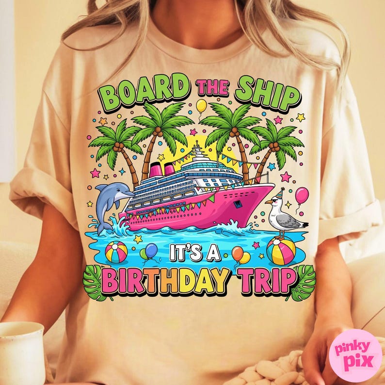 May include: Beige t-shirt with a colourful graphic. The design features a pink cruise ship, palm trees, a dolphin, and a seagull. Text reads "BOARD THE SHIP" and "IT'S A BIRTHDAY TRIP". Balloons and stars complete the festive design.