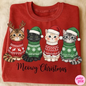 以下が含まれることがあります： クリスマスセーターと帽子をかぶった4匹の漫画の猫が描かれた赤いスウェットシャツ。猫はトナカイの角とサンタの帽子で飾られています。「Meowy Christmas」というフレーズが下部に書かれています。