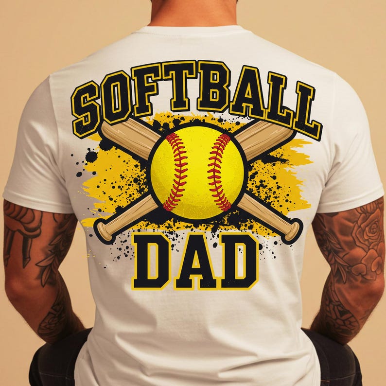 May include: White t-shirt with a softball-themed graphic. The design features a yellow softball, crossed baseball bats, and the words "SOFTBALL DAD" in a bold, black and yellow font. The design is on the back of the shirt.