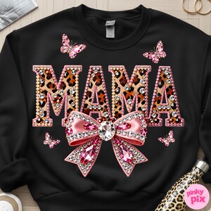 May include: Black sweatshirt with the word "MAMA" in leopard print letters outlined with pink rhinestones. A large pink bow with a crystal center and pink rhinestone accents is below the word. Pink butterflies are scattered around the design.