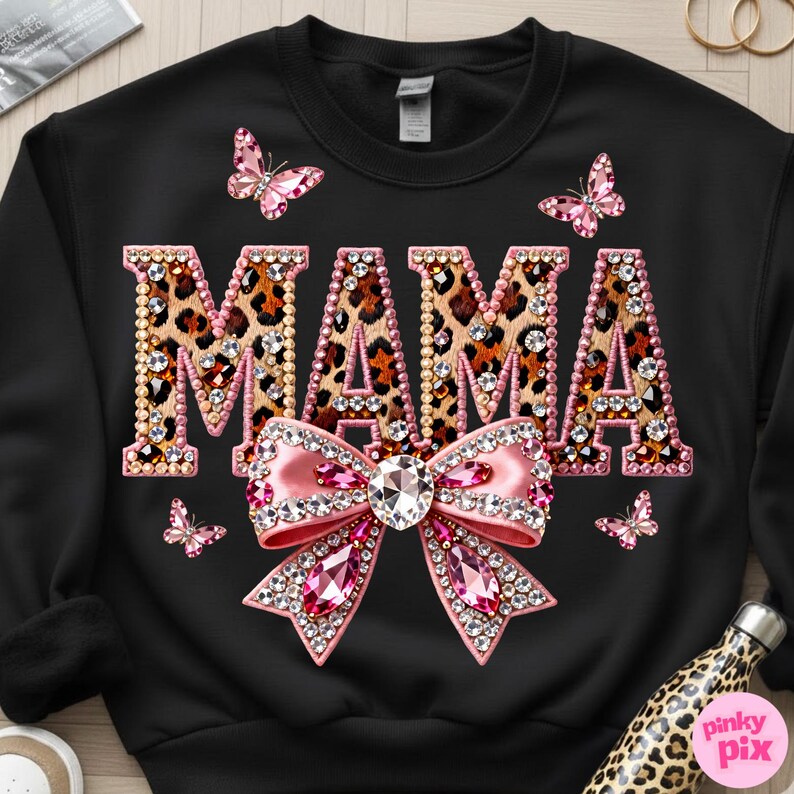 May include: Black sweatshirt with the word "MAMA" in leopard print letters outlined with pink rhinestones. A large pink bow with a crystal center and pink rhinestone accents is below the word. Pink butterflies are scattered around the design.