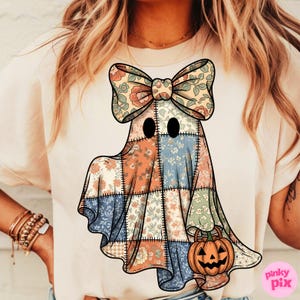 May include: A cream-colored t-shirt featuring a patchwork ghost design with a floral bow and a jack-o'-lantern. The ghost is made of various floral patterned fabrics in shades of orange, blue, and green, with black eyes. A fun Halloween-themed graphic.
