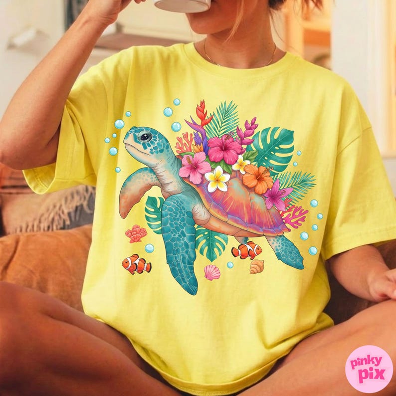 May include: Yellow t-shirt featuring a colorful illustration of a sea turtle adorned with flowers and tropical foliage. The design includes bubbles, fish, and seashells. The shirt is a relaxed fit.
