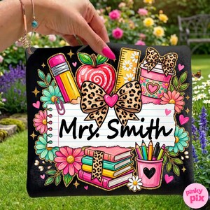 May include: Black decorative pillow with a colorful teacher-themed design. Features a pencil, apple, ruler, coffee cup, books, and pencils. The text "Mrs. Smith" is displayed on a lined paper background, surrounded by flowers and hearts.